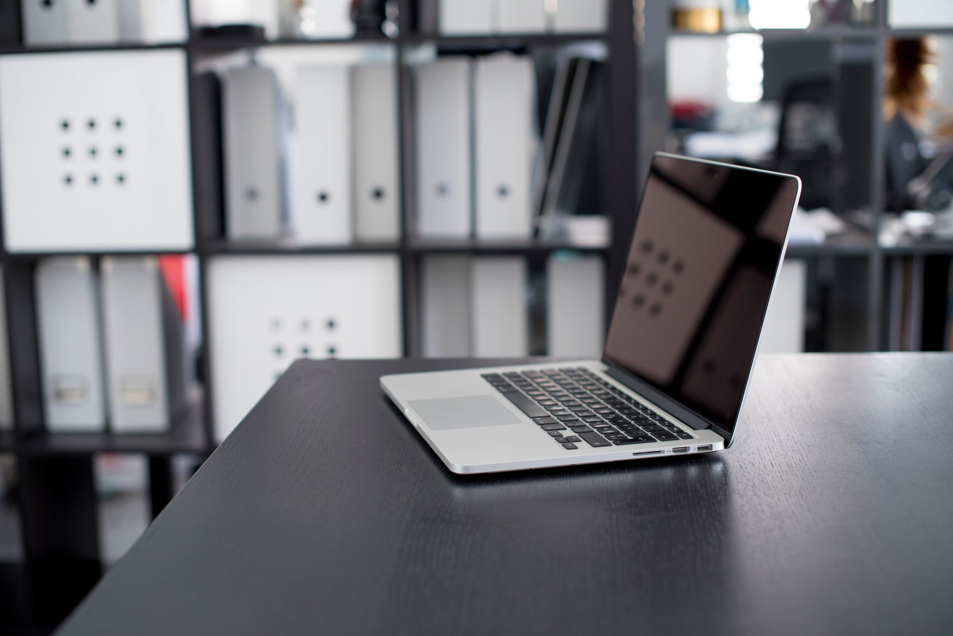 A laptop and closed folders on an office desk.