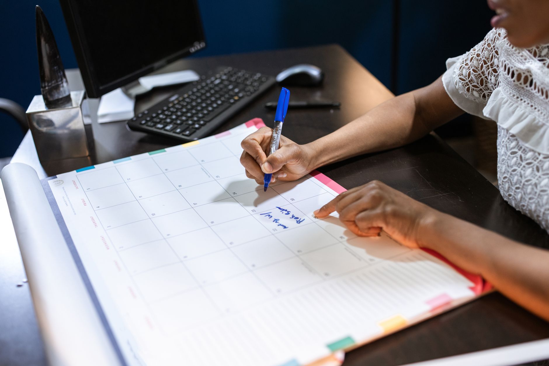A paper desk calendar and a pen on a desk.
