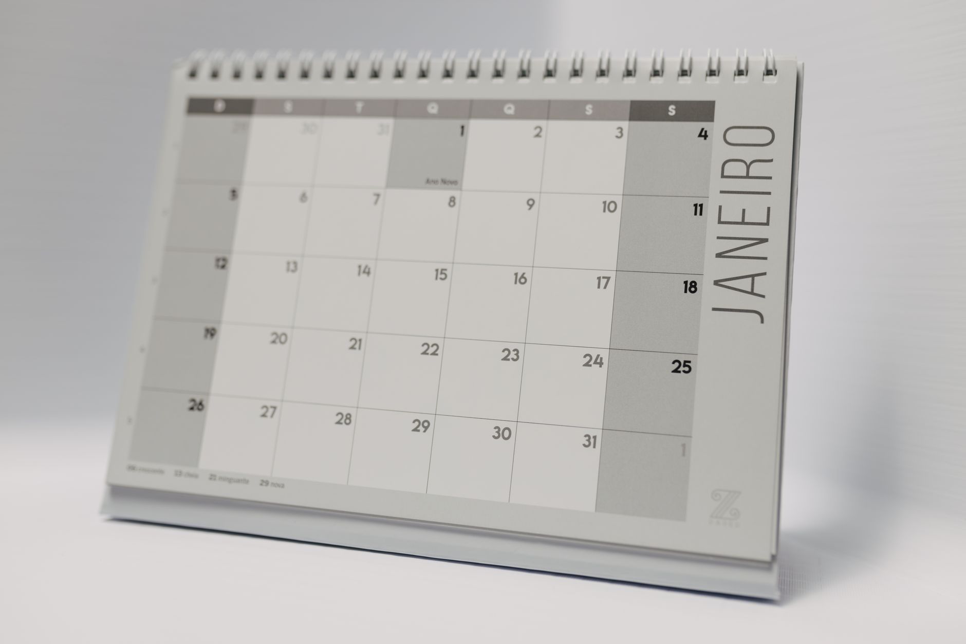 A desk planner and a pen next to a wall calendar.
