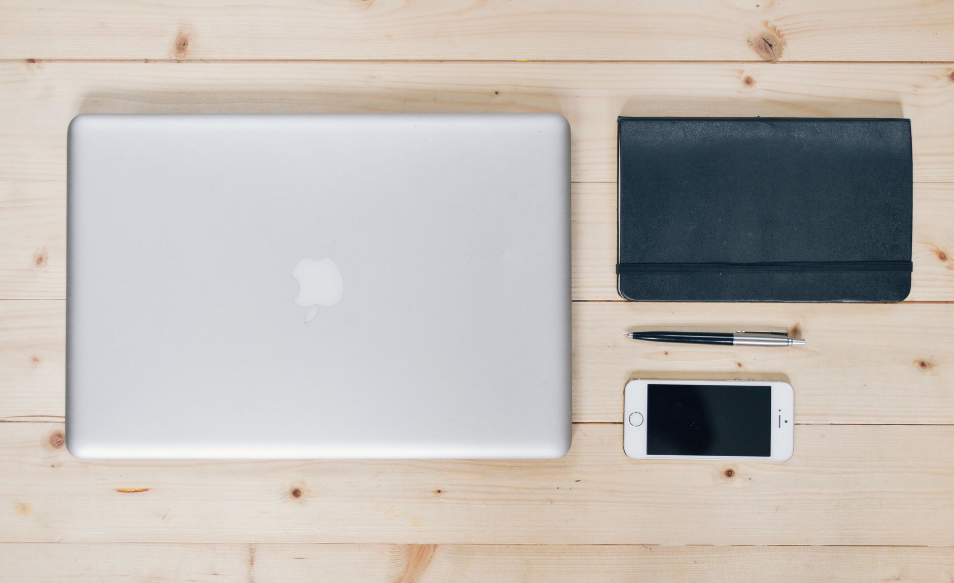 A calculator, a notebook and a stack of papers on a desk.