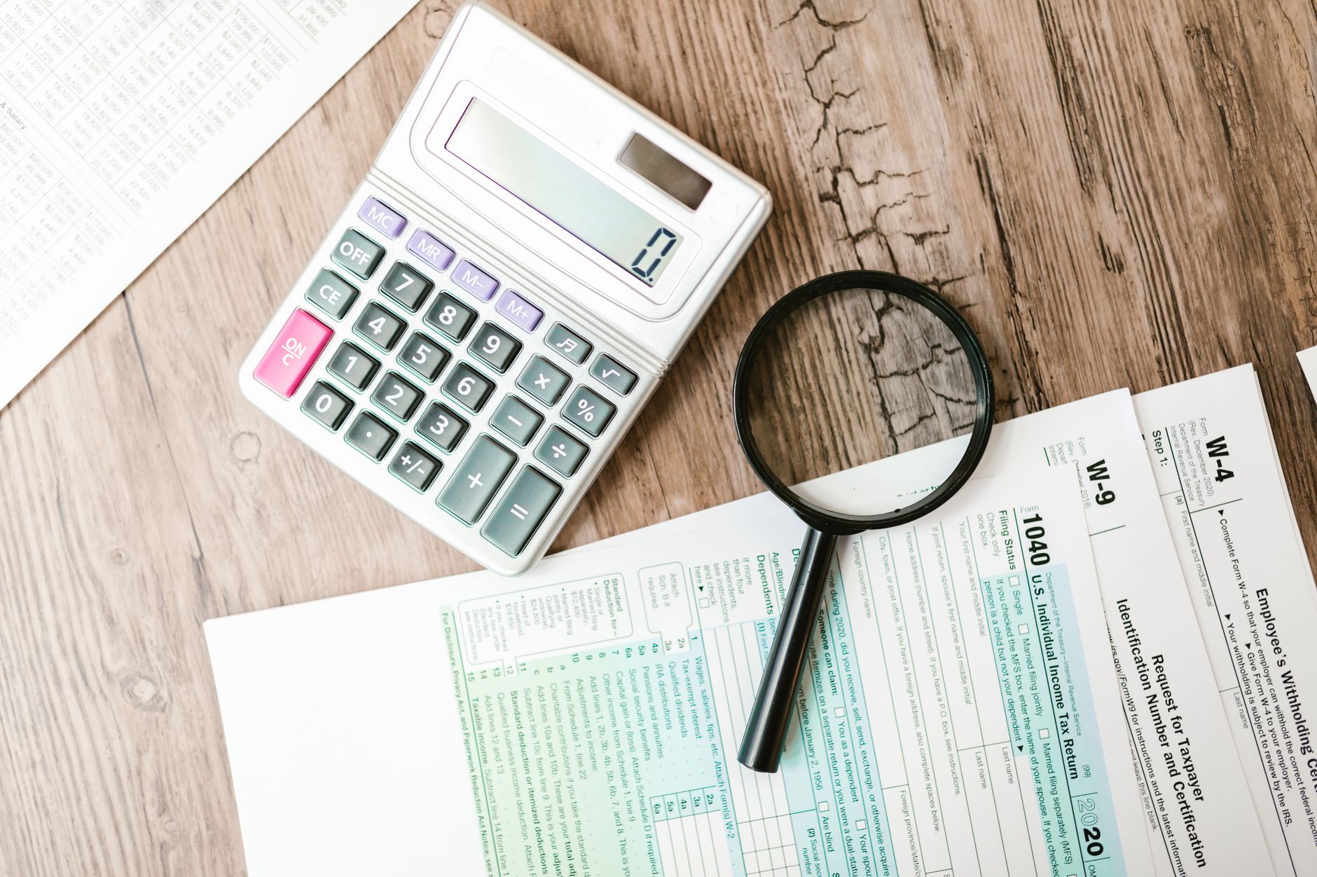 Tax documents, a calculator and a laptop on a desk, seen from above.